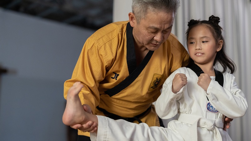 Teacher helping child with a martial arts activity